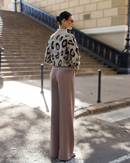 Woman wearing a leopard print sweater and beige pants on a city street.