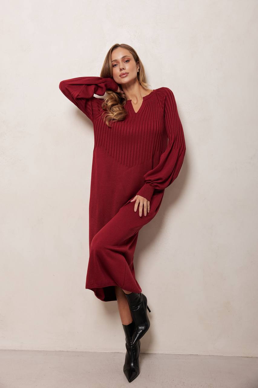 Woman wearing a burgundy dress with wide sleeves against a white background
