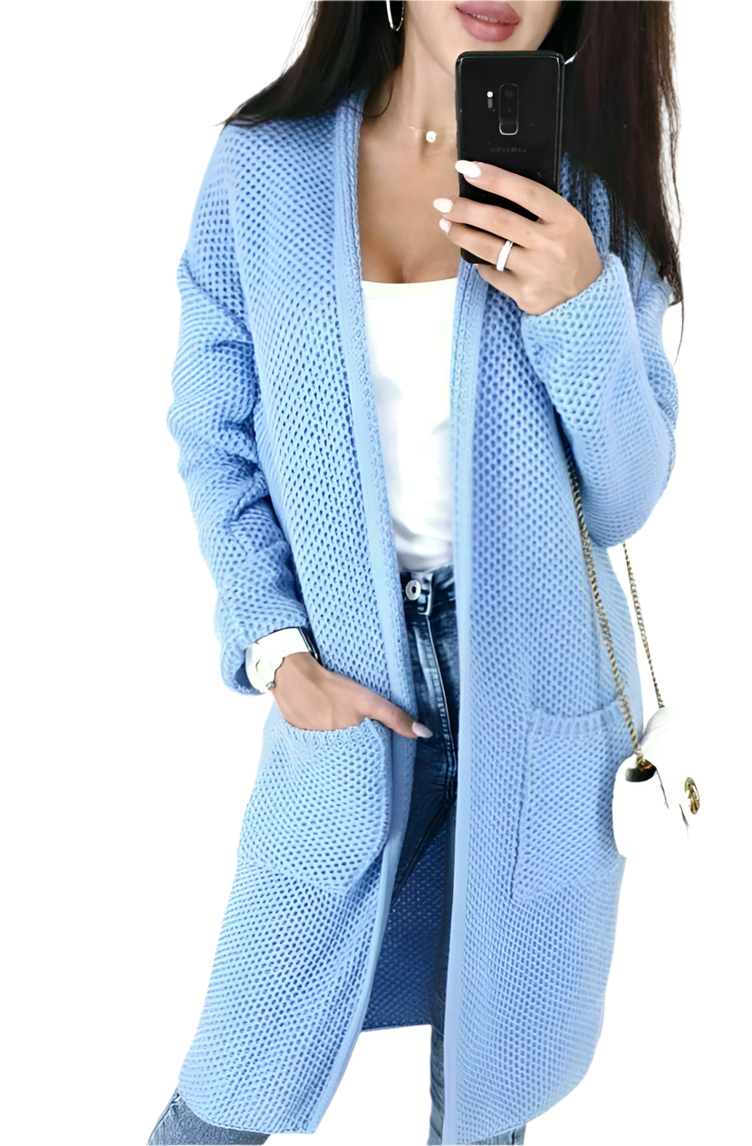 Person wearing a light blue cardigan with a white top and jeans, holding a phone.
