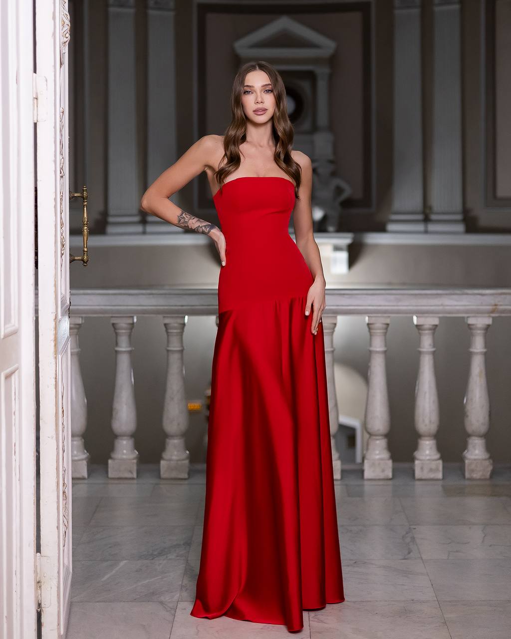 Woman in a red dress standing in an elegant interior setting