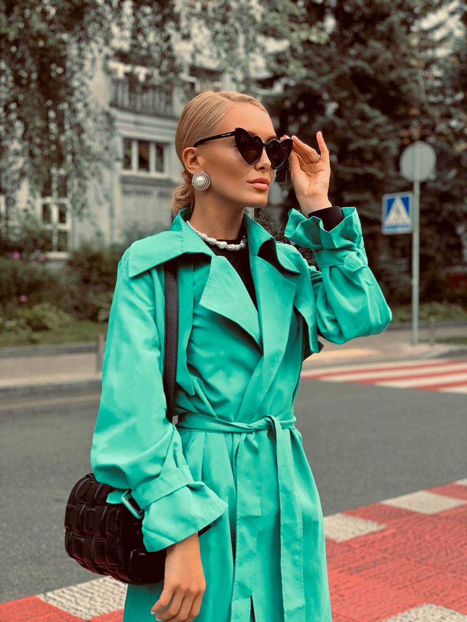 Woman in a turquoise coat standing on a street corner