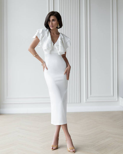Woman wearing a white dress with ruffled sleeves in a minimalistic setting