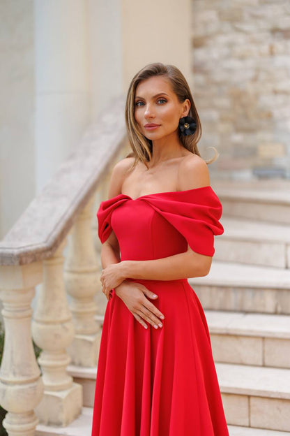 Woman in a red off-shoulder dress standing outdoors with columns in the background