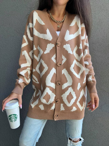 Person wearing a patterned brown cardigan holding a Starbucks cup against a gray background