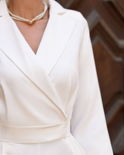 White dress with a pearl necklace against a blurred background