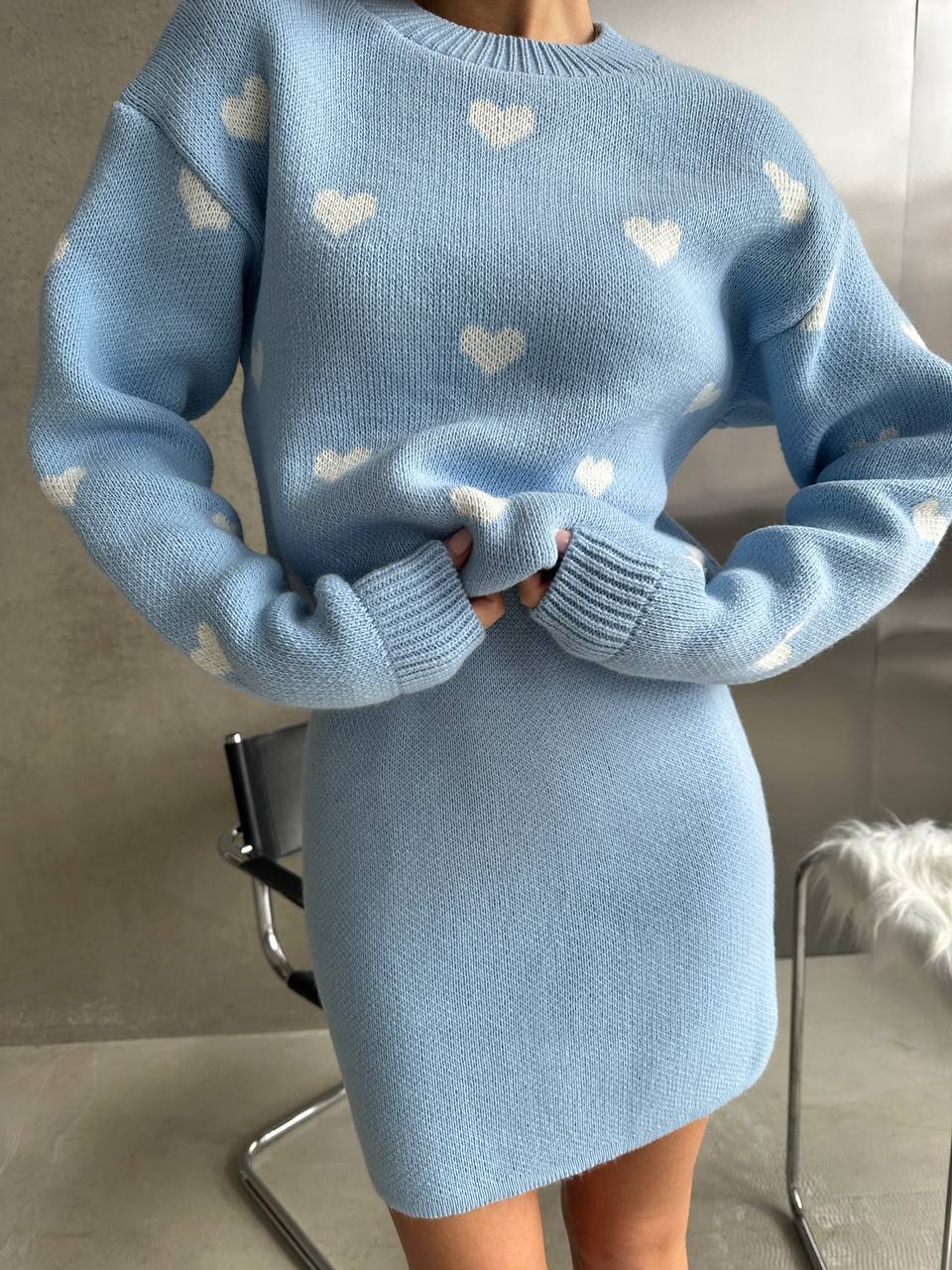 Light blue sweater dress with heart patterns worn by a person indoors.