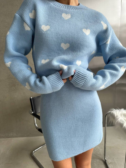 Light blue sweater dress with heart patterns worn by a person indoors.