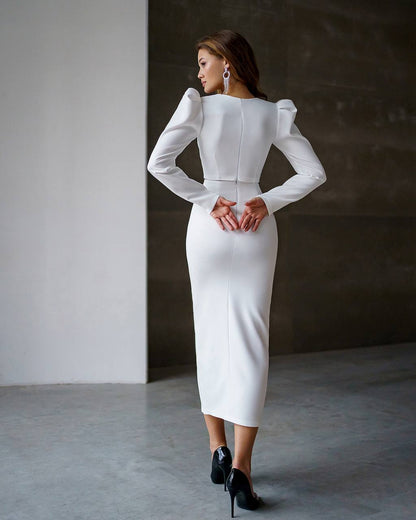 Woman wearing a white dress with long sleeves in a minimalistic setting