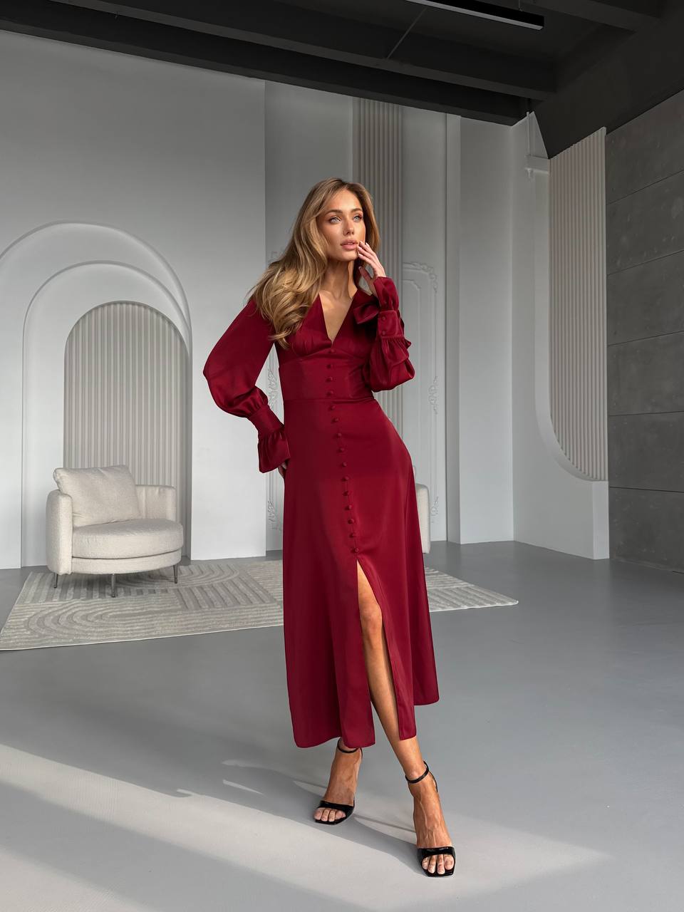 Woman in a burgundy dress standing in a modern interior setting