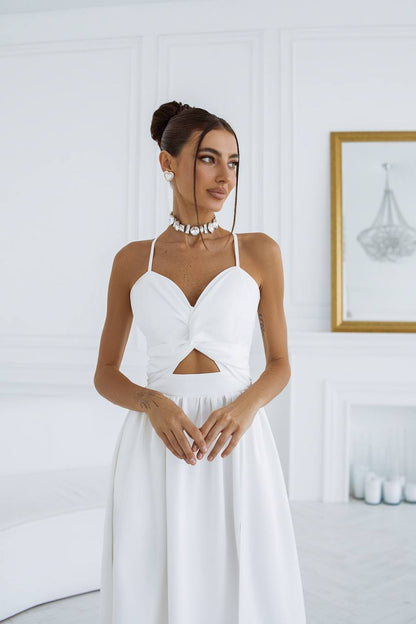 Woman wearing a white dress with a cutout design in a minimalistic room.