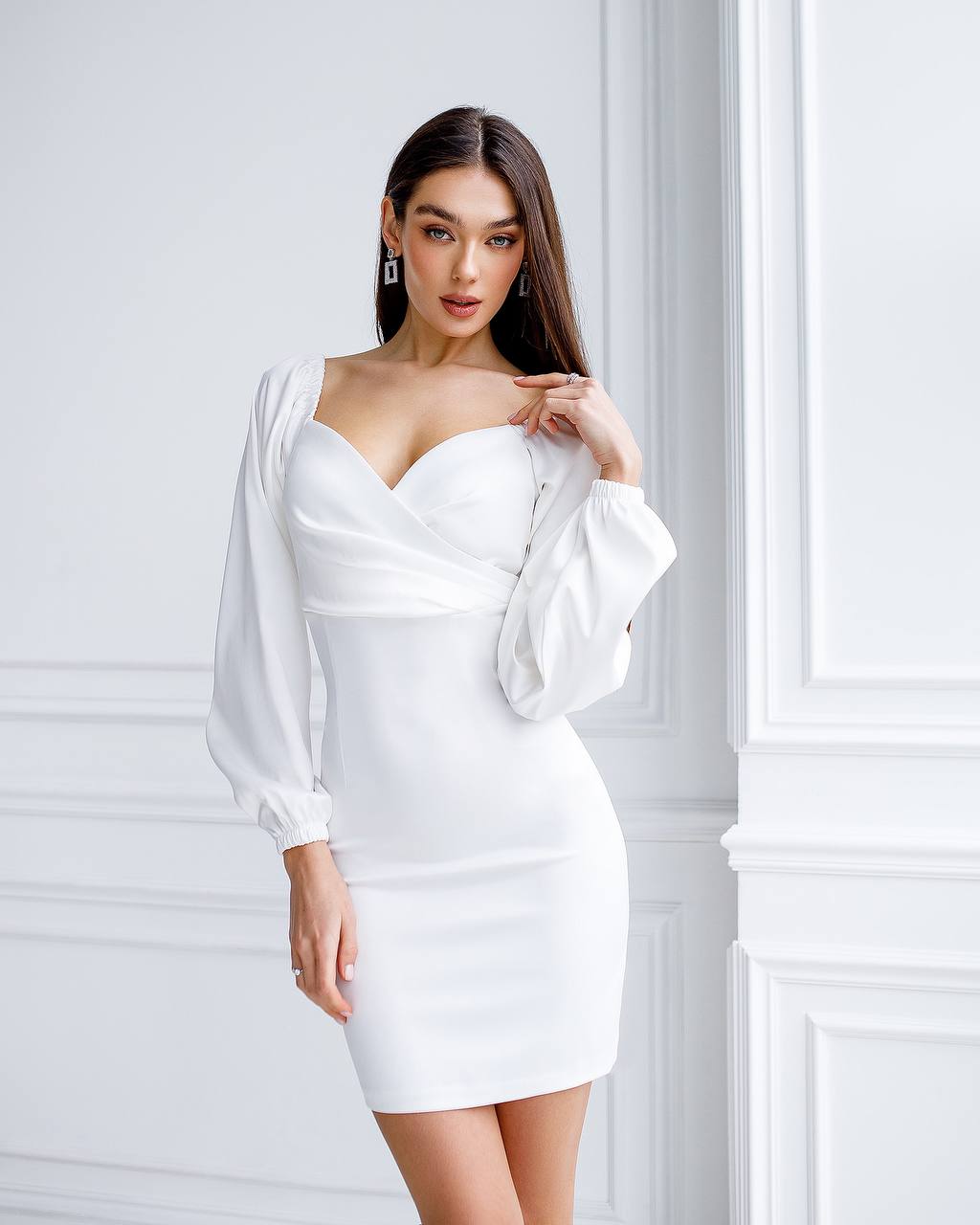 Woman wearing a white dress against a white wall