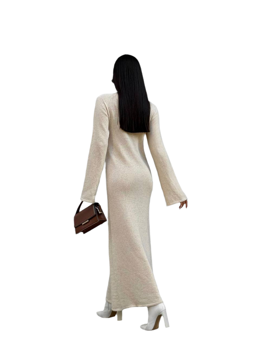 Woman in a long beige dress holding a brown handbag on a white background