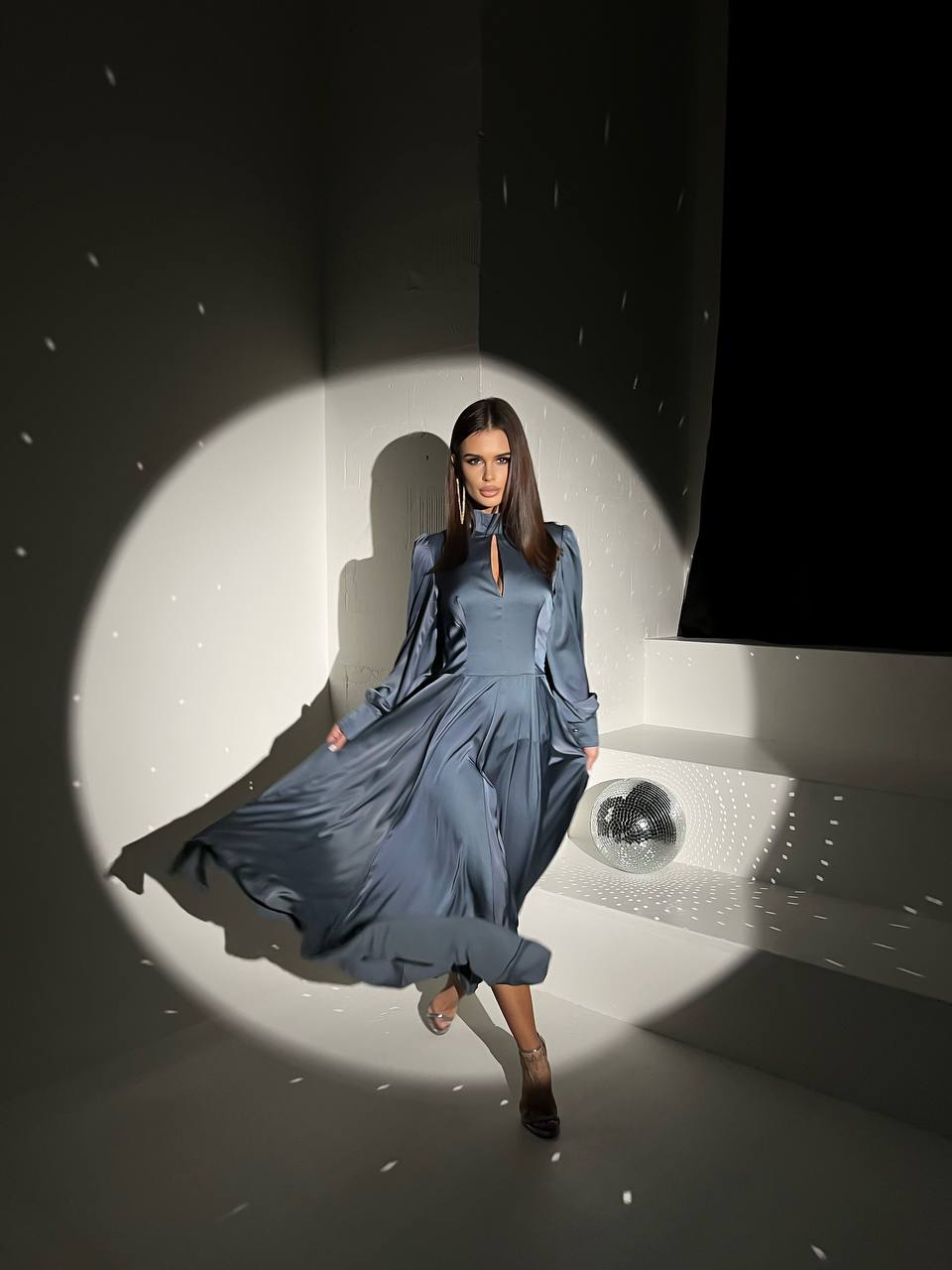 Woman in a blue dress standing in a spotlight with a dark background