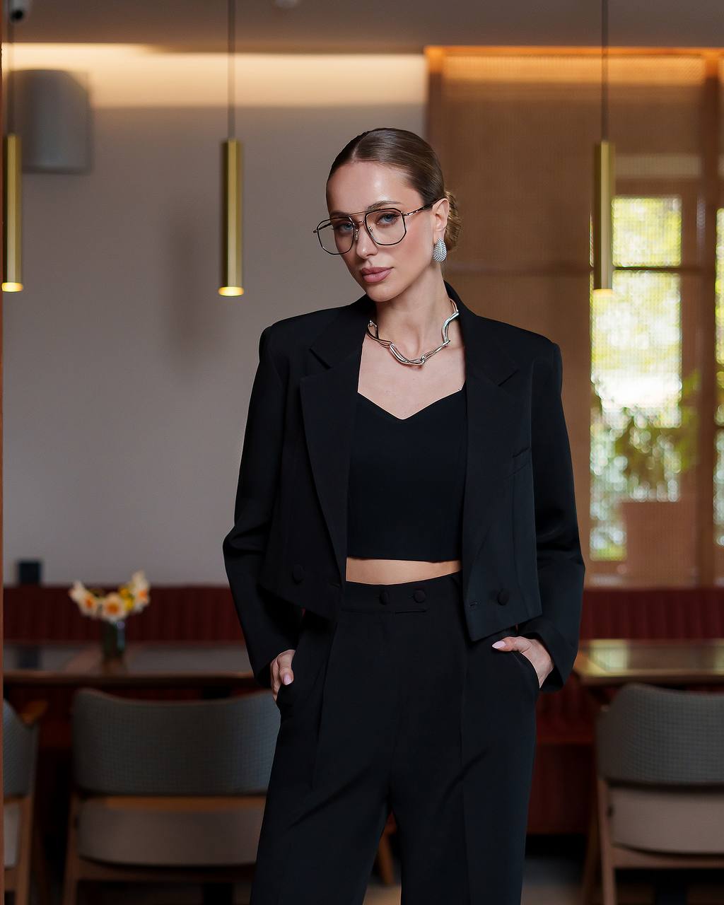 Woman in a black outfit standing in a modern interior setting