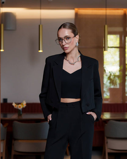 Woman in a black outfit standing in a modern interior setting