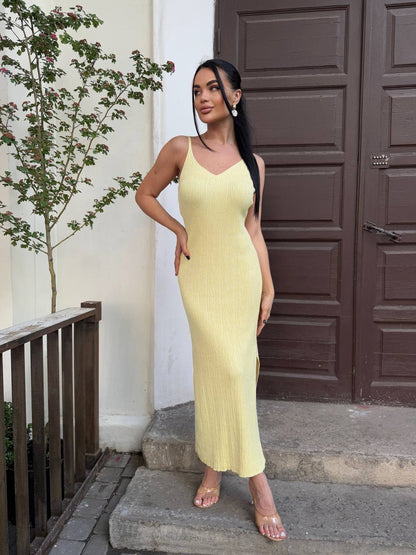 Woman in a yellow dress standing on steps with a plant and door in the background