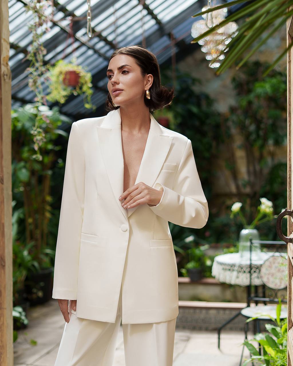 Woman in a white suit standing in a greenhouse setting