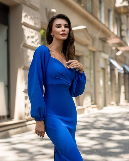 Woman in a blue dress standing on a street with buildings in the background