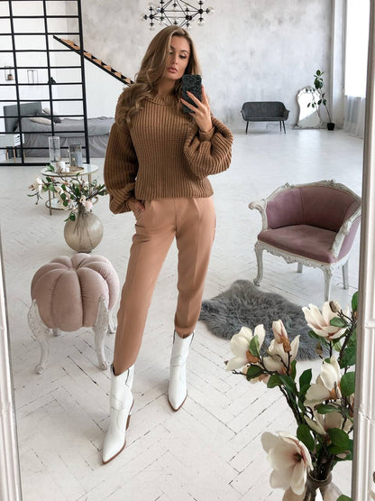 Woman taking a mirror selfie in a stylish outfit with a neutral color scheme.