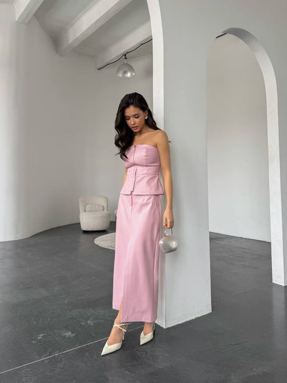 Woman in a pink strapless outfit standing in a minimalistic room.
