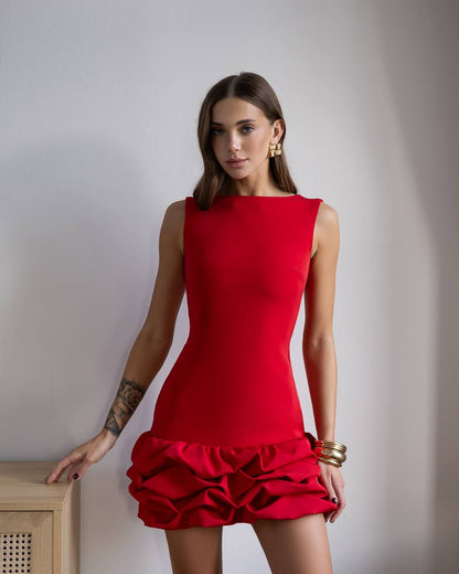 Woman wearing a red dress with ruffled skirt against a plain background