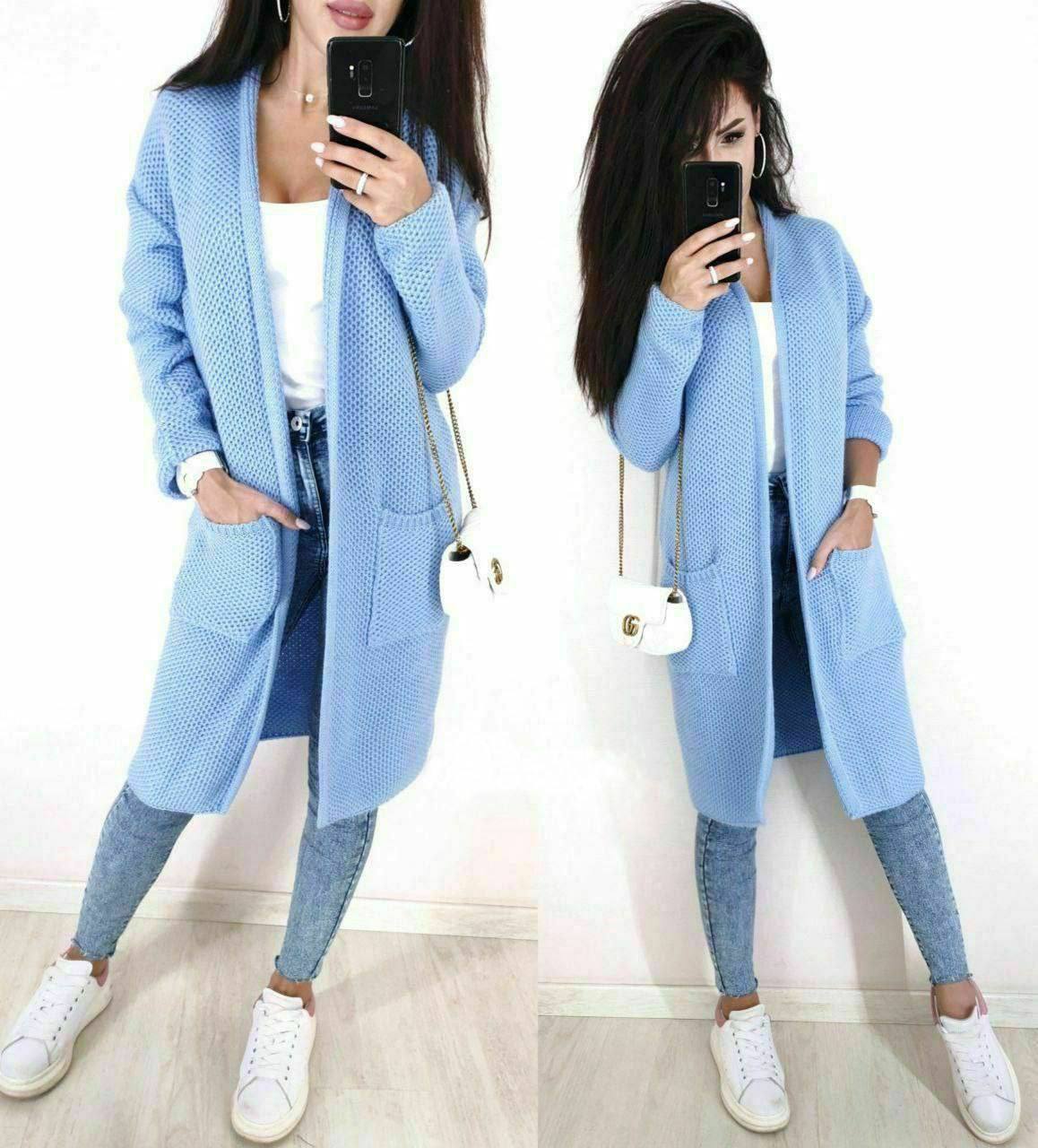 Woman wearing a long light blue cardigan and matching pants, standing on a light wooden floor.