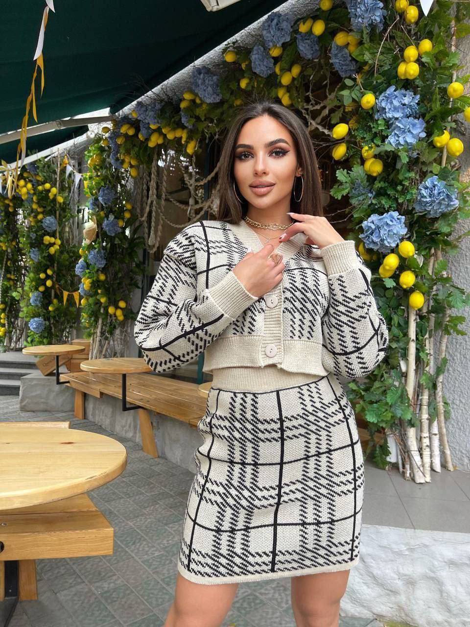 Woman in a patterned outfit standing in front of floral decorations