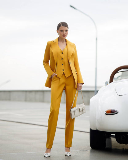 Woman in a yellow suit standing next to a white car with a blurred background