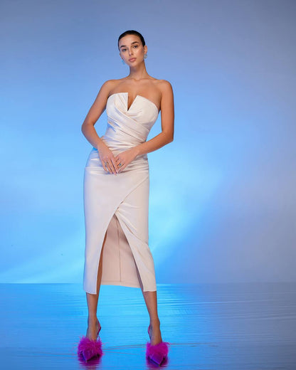 Woman wearing a white strapless dress with a slit on a blue gradient background