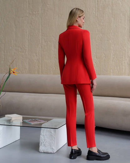 Woman in a red suit standing in a modern living room.