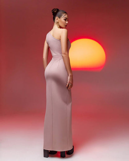 Woman in a long, elegant dress standing against a gradient background with a warm light.