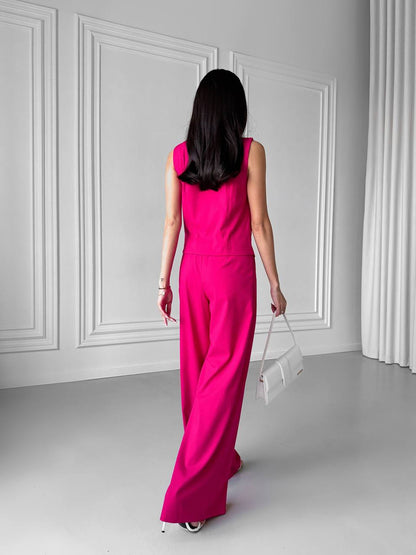 Woman in a bright pink dress standing in a minimalistic room with white walls and floor.