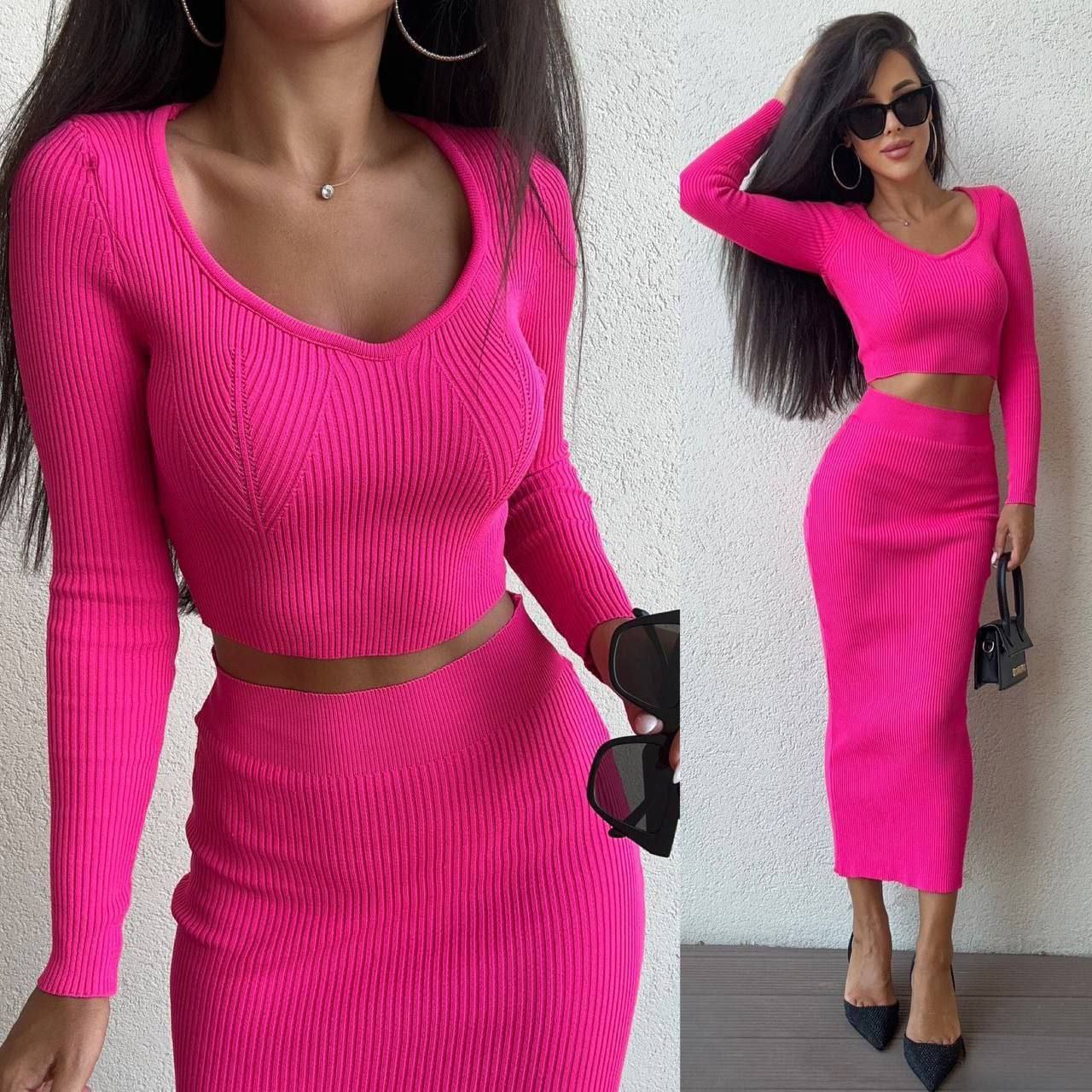 Woman wearing a bright pink two-piece outfit against a neutral background
