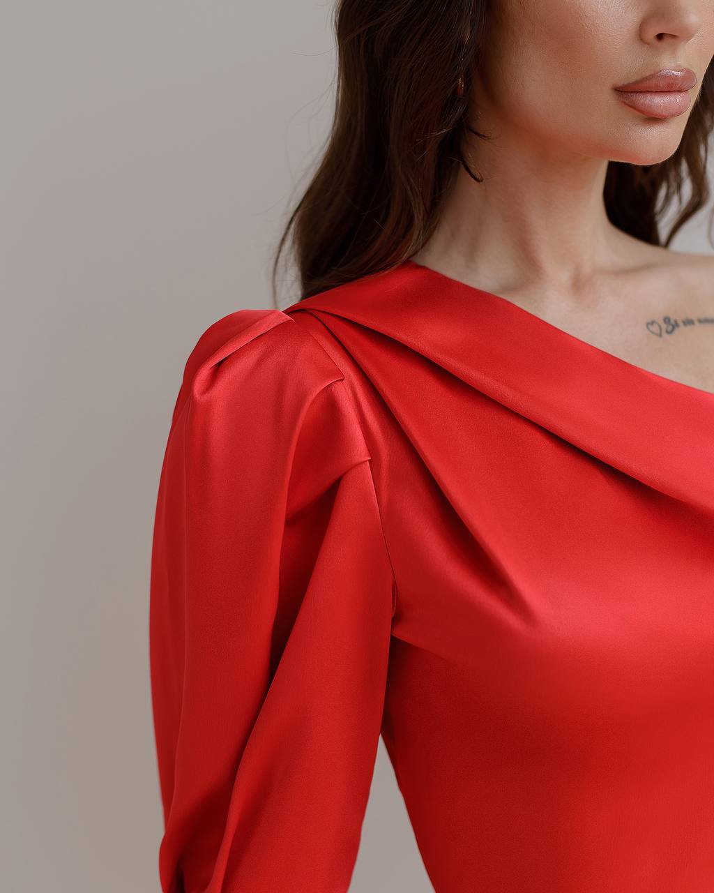 Red one-shoulder dress worn by a model against a neutral background