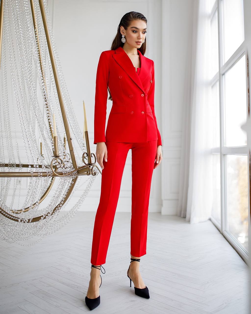 Woman wearing a red suit in a bright room with large windows.
