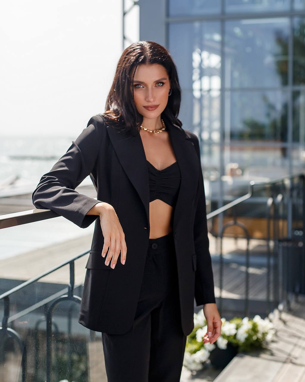 Woman in a black suit standing outdoors with a blurred background