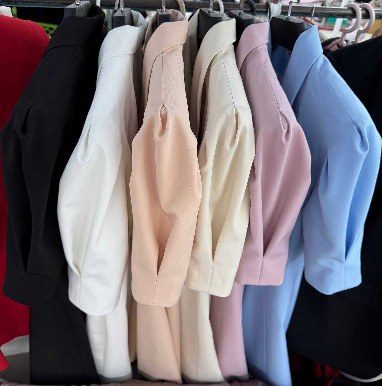 Row of blazers in various colors hanging on a rack.