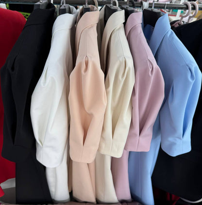 Row of blazers in various colors hanging on a rack.