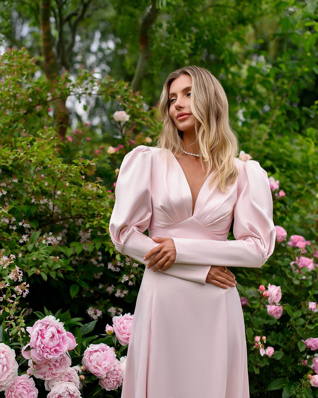 Woman in a pink dress standing in a garden with flowers