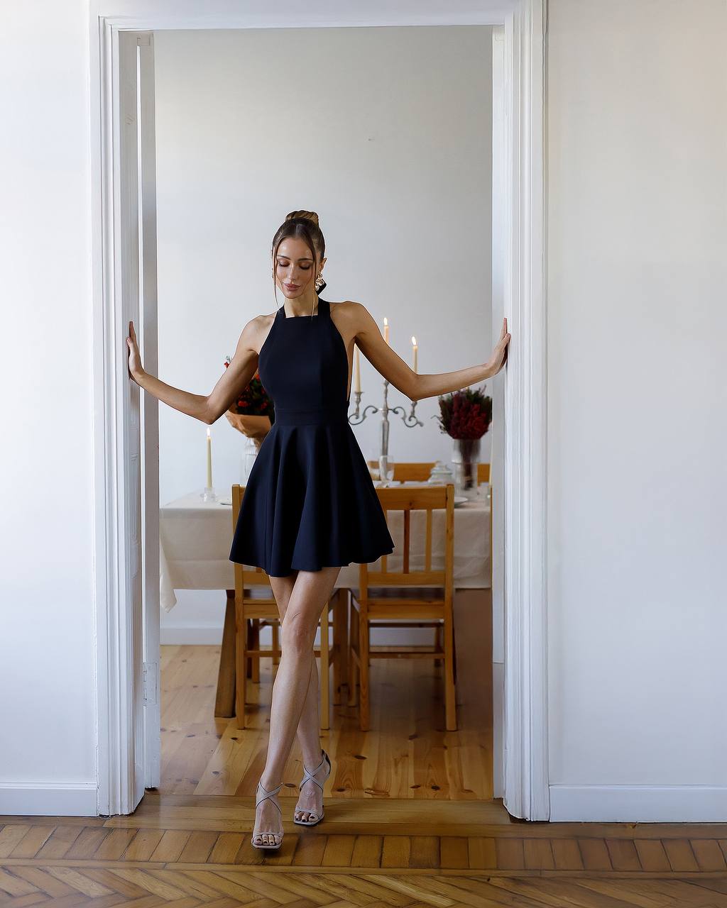 Woman in a black dress standing in a doorway with a dining room in the background