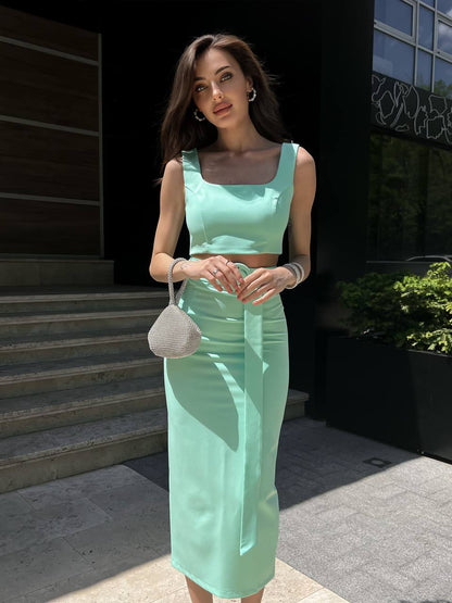 Woman in a light green dress standing outdoors on a sunny day.