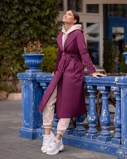 Woman in a purple coat standing on a blue railing with a blurred background