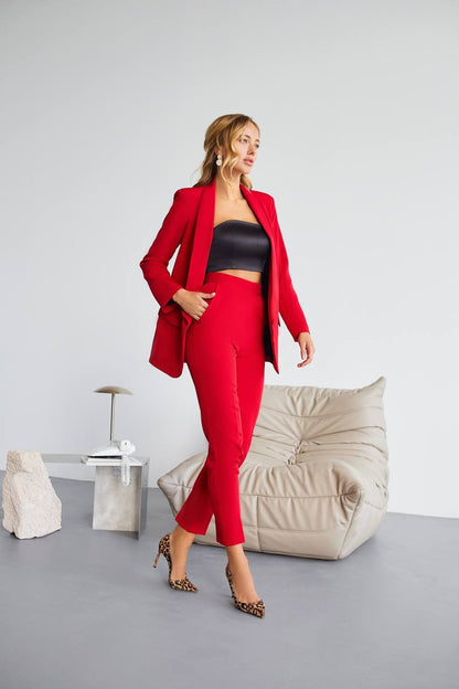 Woman in a red suit standing in a modern room with a gray floor and white walls.