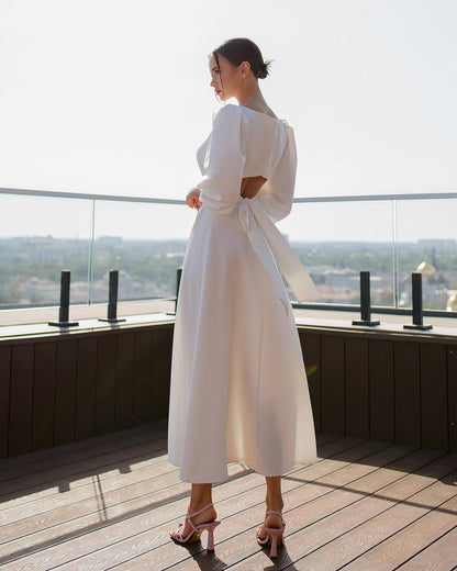 Woman in a white dress standing on a rooftop with a cityscape view