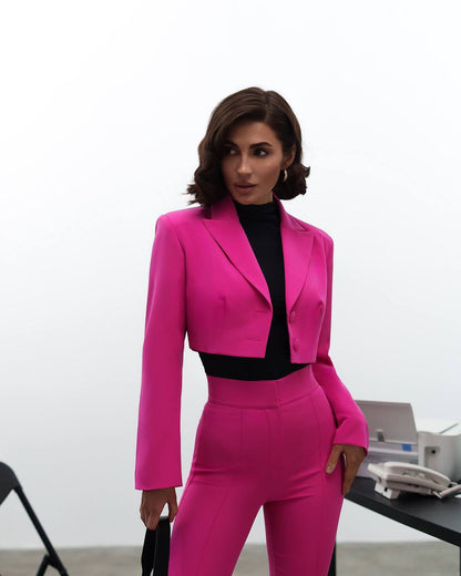 Woman wearing a bright pink suit with a black top in an office setting.
