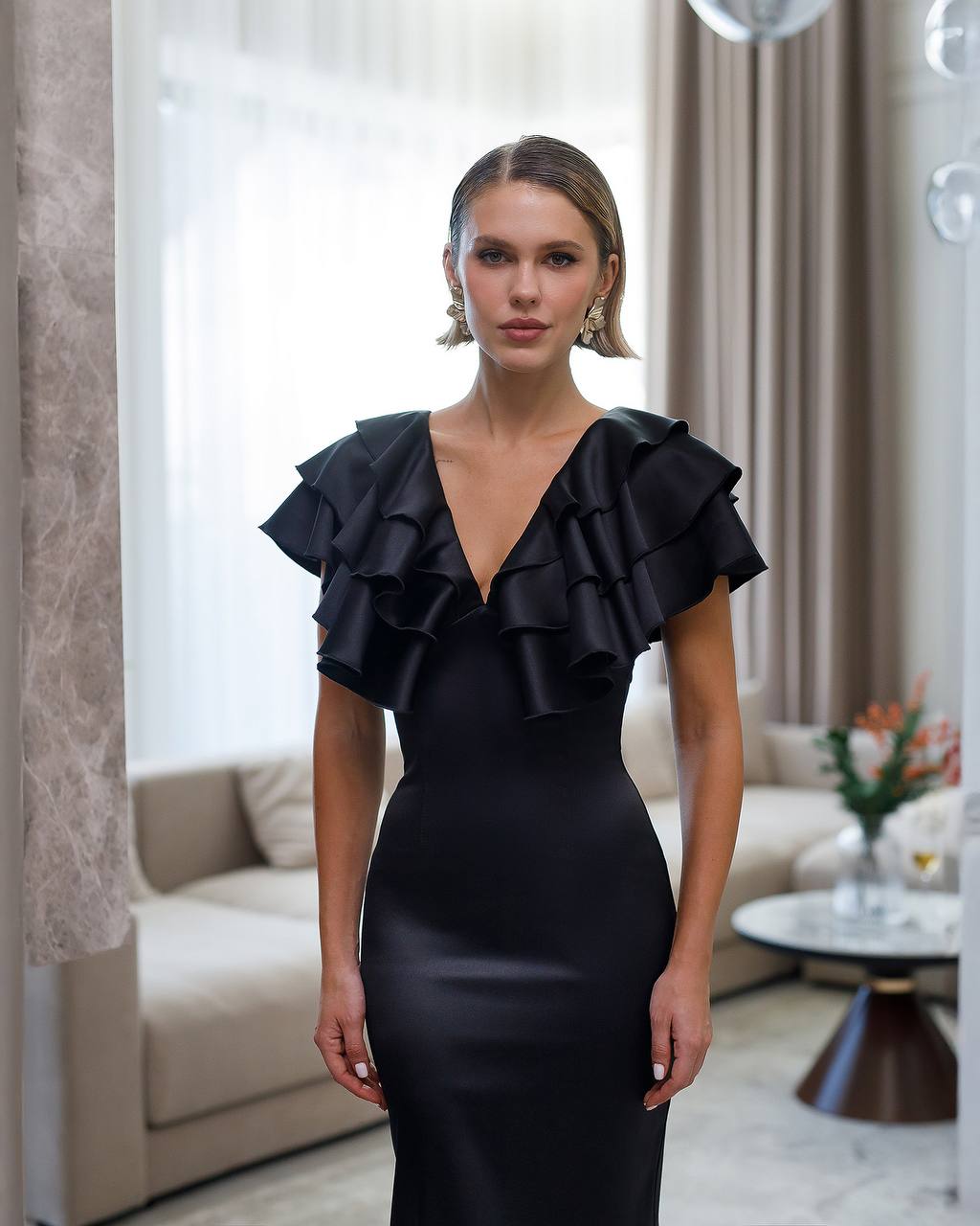Woman wearing a black ruffled dress in an elegant room.