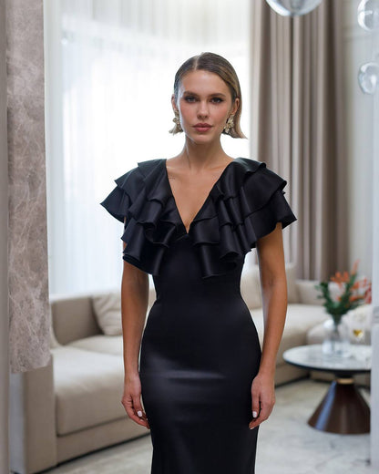 Woman wearing a black ruffled dress in an elegant room.