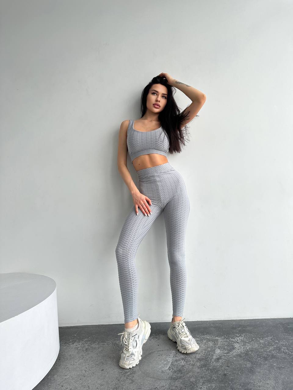 Woman wearing a gray athletic outfit posing against a plain background