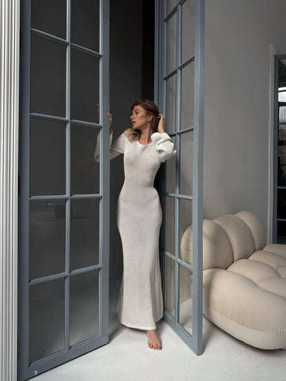 Woman in a white dress standing in a room with a modern interior design.