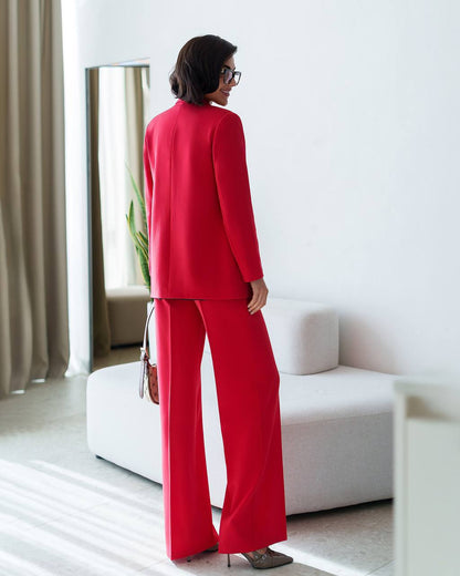 Woman in a red suit standing in a modern living room.